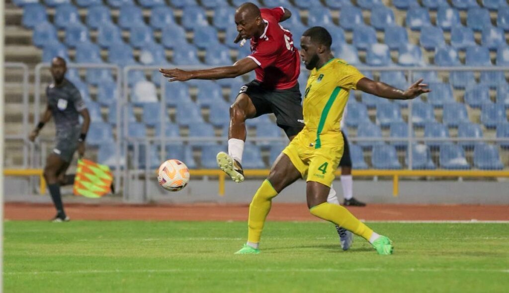 Trinidad and Tobago striker Kevon Woodley (L) shoots at goal while under pressure from Guyana’s Jeremy Grant during a friendly match at the Hasely Crawford Stadium in Port of Spain, on Monday night. - Daniel Prentice