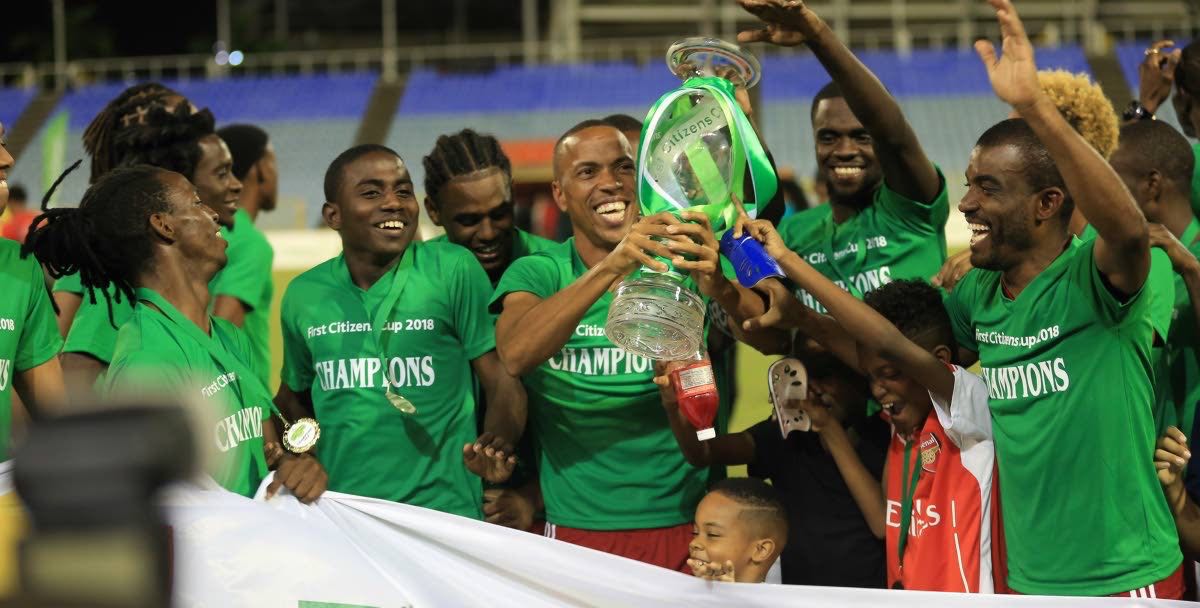 Central FC captain Densill Theobald, centre, lifts the First Citizens Cup trophy as teammates celebrate around him after Friday's final vs Defence Force at the Hasely Crawford Stadium, Mucurapo.