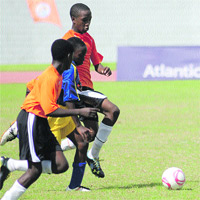 Leading by example: Primary schools MVP, Bon Accord Government captain Jabarry Francis, far side, takes the attack to these Whim Primary School defenders. Two Francis goals led Bon Accord to a 2-1 extra-tima win in the final of the Atlantic National Primary School final yesterday at the Dwight Yorke Stadium, Bacolet. —Photo: Ian Prescott