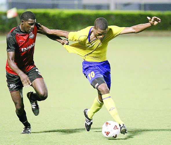 Keion Goodridge, left, of bmobile Joe Public pulls on the jersey of Defence Force’s Kerry Joseph during their Toyota Classic quarterfinal at the Marvin Lee Stadium, Macoya on Tuesday night. Joe Public won 2-1. (Photo: T&T Guadrian)