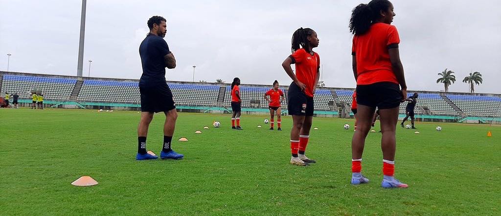 New assistant coach Carlos Edwards, left, looks on as head coach Kenwyne Jones, extreme right, delivers instruction to his players, including Cayla Mc Farlane, second from left, Kadeen Jack, third from left, Amaya Ellis, fourth from left, and Rhea Belgrave ahead of today's World Cup qualifying clash with Nicaragua at the Hasely Crawford Stadium, Mucurapo from 3 pm.