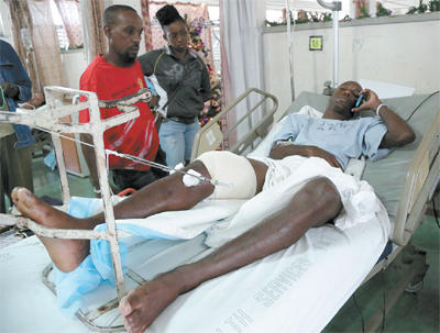 National senior footballer Keron Cummings speaks on his cell phone while warded at the Port-of-Spain General Hospital after being shot in the leg after returning home from a party on Saturday. Cummings was expected to join the national team in camp ahead of the Copa America Centenario match against Haiti on January 8. Photo: MARCUS GONZALES