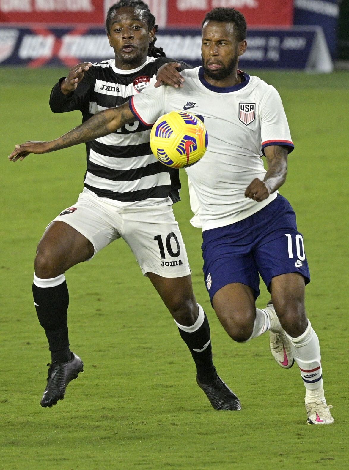 Photo: Trinidad and Tobago midfielder Duane Muckette (left) competes with USA midfielder Kellyn Acosta for the ball during international friendly action in Orlando on 31 January 2021. ...(Copyright AP Photo/Phelan M Ebenhack)