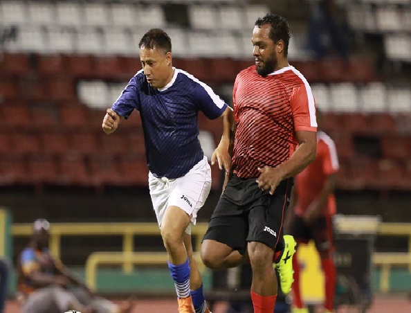 Commissioner of Police Gary Griffith (left), of Team Relief, tries to run past an opponent during the ‘Football For a Cause’ match at the Hasely Crawford Stadium,Mucurapo, on Friday night.