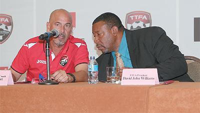 T&T's Senior Men's football team head coach, Stephen Hart, left, and TTFA president David John Williams share a few words during yesterday's unveiling of the TTFA's newest sponsor, SCG (Caribbean) Group Limited at Hyatt Regency, Port-of-Spain. Photo: MARCUS GONZALES