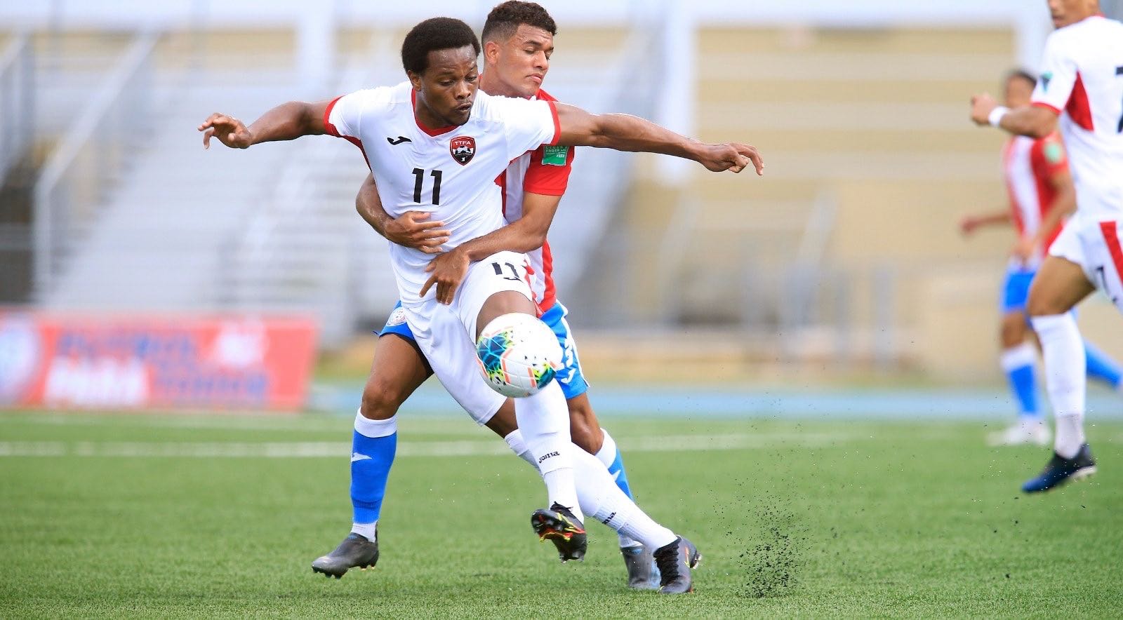 Photo: Trinidad and Tobago flanker Levi Garcia (front) is watched closely by a Puerto Rico defender during their 2022 World Cup qualifying contest at the Estadio Centroamericano in Mayaguez on 28 March 2021. (via TTFA Media)