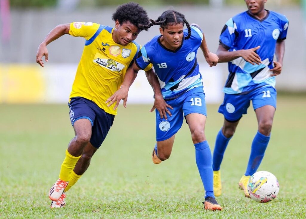 Malick's Keston Singh (C) wins the duel for possession against Speyside's Omar Daniel (L) during the Secondary School Football League premiership match at the St Mary's College grounds on Saturday, in Port of Spain. - DANIEL PRENTICE