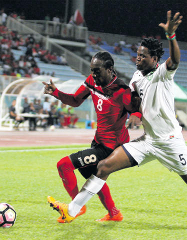 T&T midfielder Nathan Lewis, left, holds off Suriname’s Guno Kwasie during action in last evening’s CFU Gold Cup play-off qualifier at Ato Boldon Stadium in Couva. PHOTO: ANTHONY HARRIS.