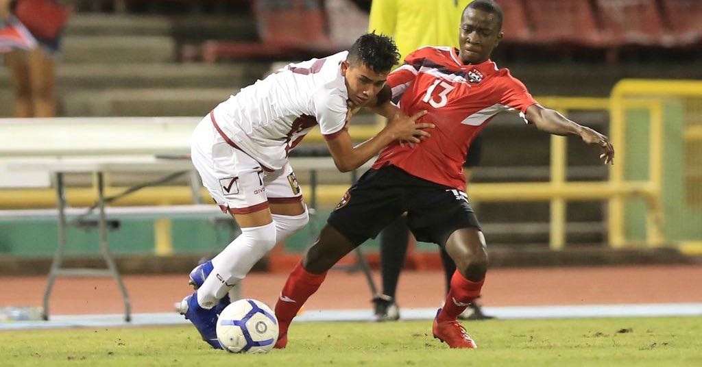 T&T's Kassidy Davidson, right, is held off by Venezuela's Klinsmann Gomez (#7), during the TTFA Boys Under-15 Invitational Tournament between T&T and Venezuela at the Hasely Crawford Stadium, Mucurapo on Friday night. ...Allan V. Crane