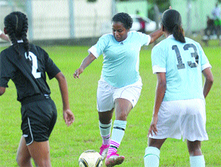 BEAVER-TRICK: Real Dimension striker Alania Burgin, centre, fires a shot between her teammate Racine Romain, right, and Arima Giants defender Ruth Wiseman, at the Barataria Oval, last Saturday. Burgin scored four goals in Real Dimension's 8-1 victory. –Photo: ANISTO ALVES