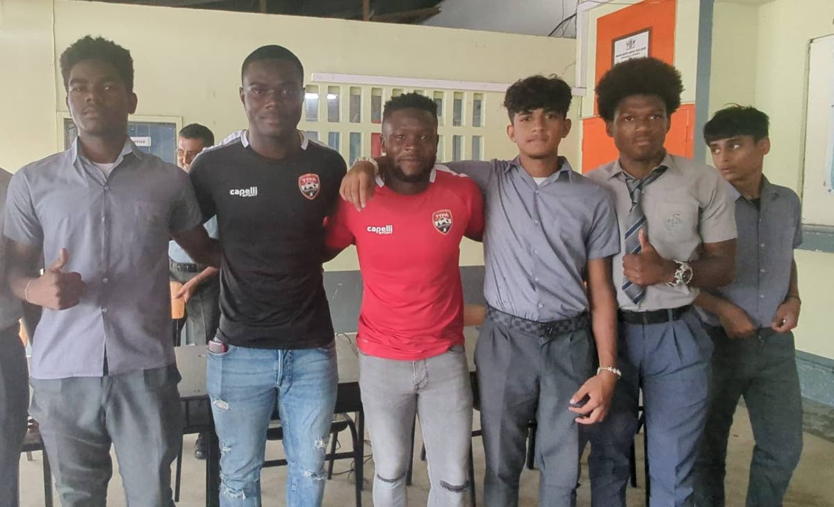 Trinidad and Tobago goalkeeper Denzil Smith (black jersey) and defender Isaiah Garcia (red jersey) pose for a photo with students of Shiva Boys Hindu College during a TTFA school tour on Wednesday, May 29th 2024.