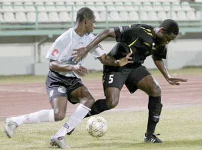 DirecTV North East Stars’ Anthony Wolfe, left, tries to elude Larry Bacchus of FC South End in their Digicel Pro Bowl qualifier at the Larry Gomes Stadium, Malabar on Friday night. Stars won 2-0. Photo: Anthony Harris.